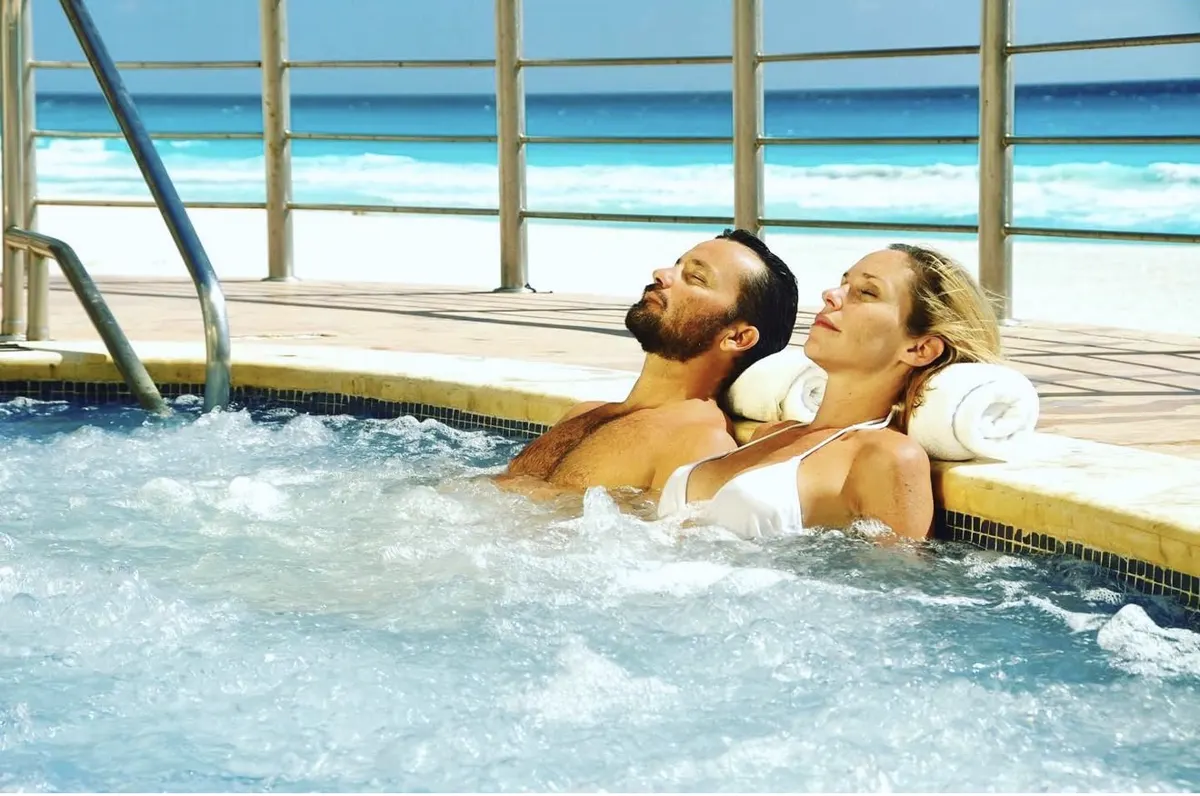 Guests relaxing in a bubbling jacuzzi on a beachfront deck with a turquoise ocean view at a Sunset World resort, Cancún & Riviera Maya, Mexico