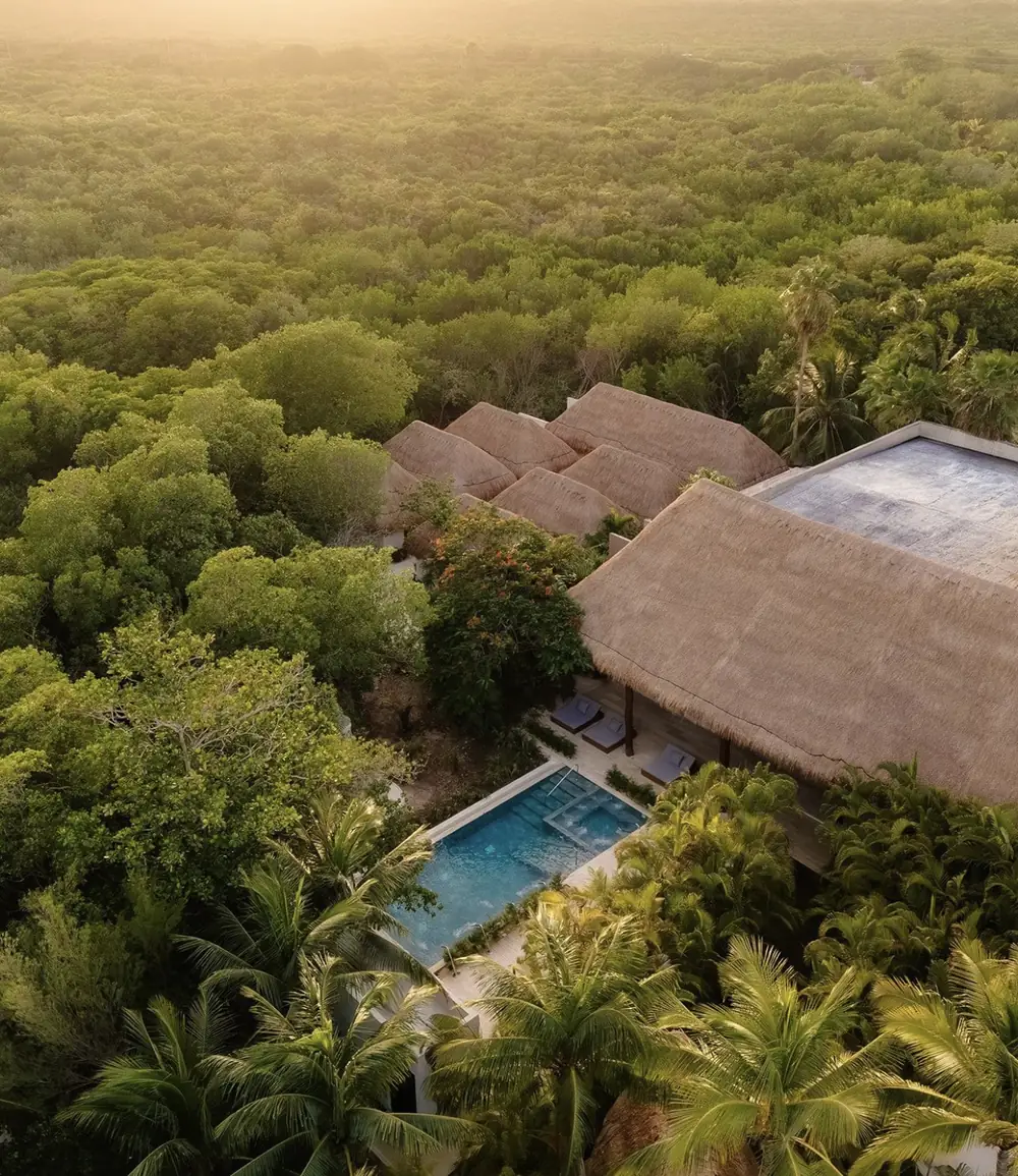 Aerial view of a jungle spa with thatched roofs and a swimming pool
